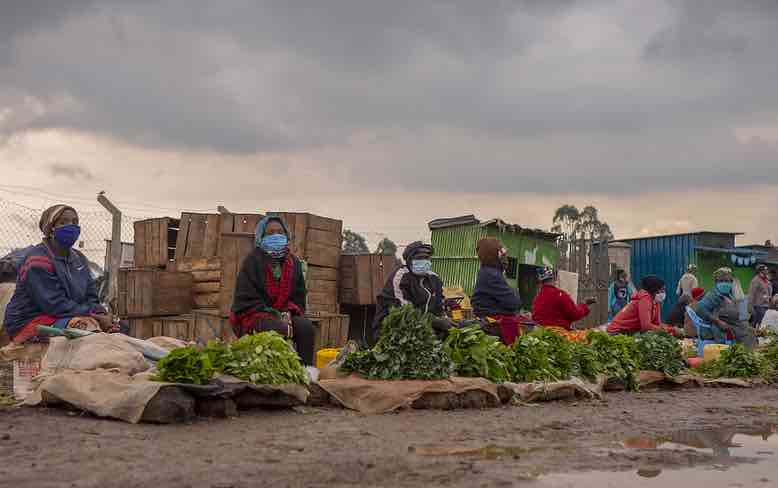 Mask-wearing vendors sell produce at a Kenya market early in the pandemic